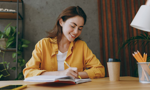 smiling woman writing in a notebook